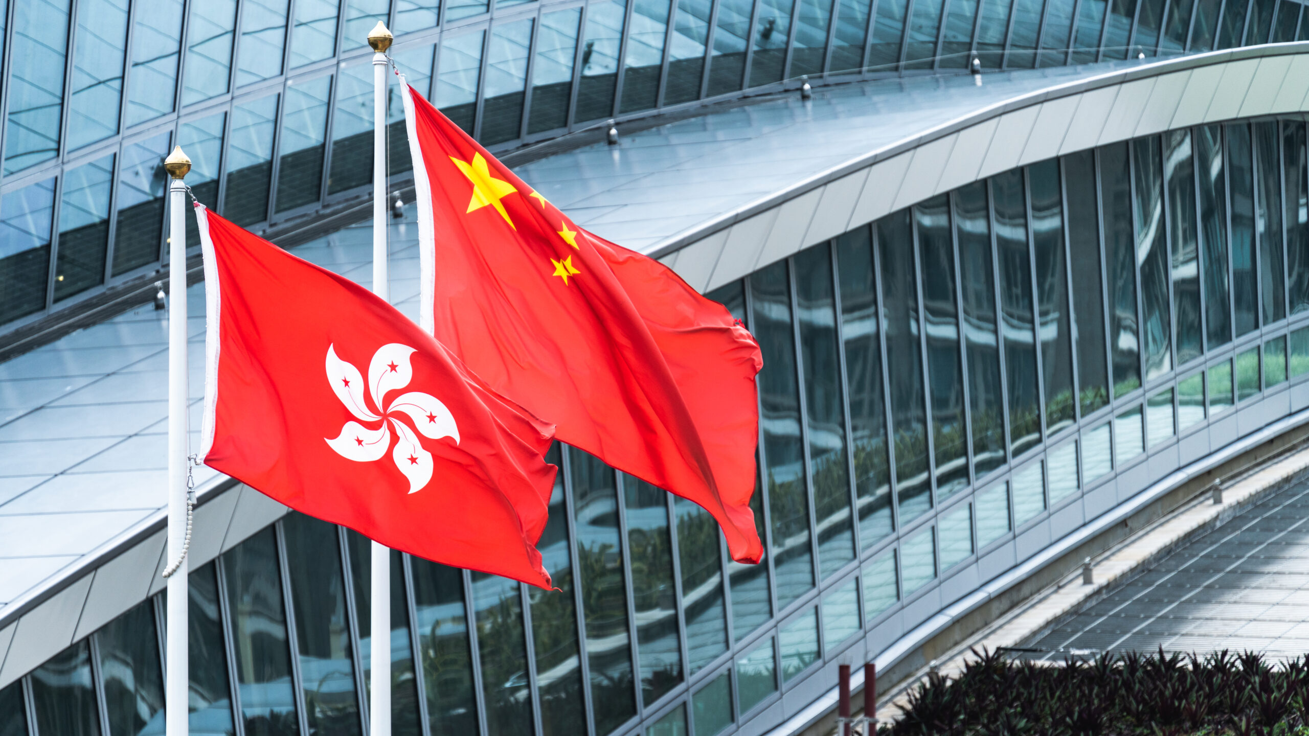 HongKongAndMainlandChinaNationalFlagsStandTogetherWith - Tokenhell Hong Kong Grants Approval for Spot Bitcoin and Ether ETFs
