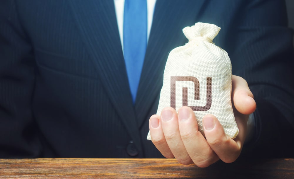 ABusinessmanHoldsInHisHandAIsraeliShekelMoney - Tokenhell NBFC-S Review 2024 – How it Can Help you Recover Crypto