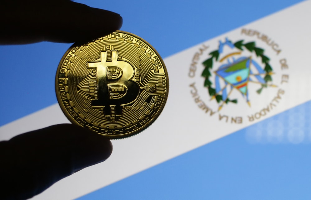 BitcoinWithElSalvadorFlagBackgroundSelectiveFocusAtThe - Tokenhell Bitcoin Adoption in El Salvador: Everything You Need to Know