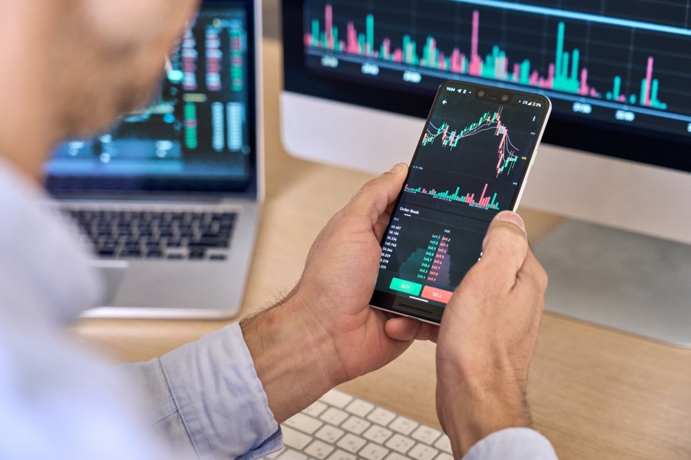 CryptoTraderInvestorBrokerUsingSmartphoneAppAnalyzingFinancialData - Tokenhell Crypto Exchange Bybit Stops Operations in France Following Regulatory Tussle