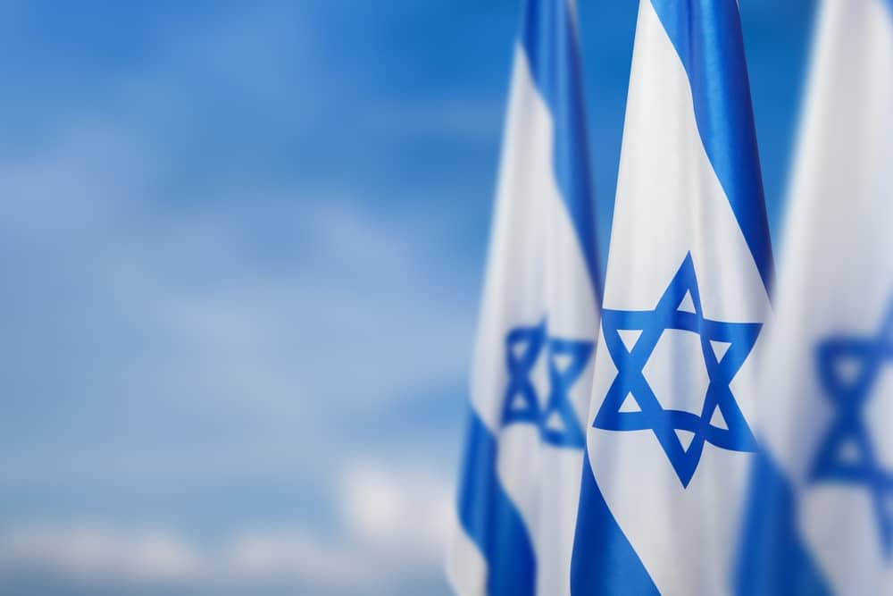 IsraelFlagsWithAStarOfDavidOverCloudySky - Tokenhell Bank of Israel Unveils Digital Shekel CBDC Pilot for Payments