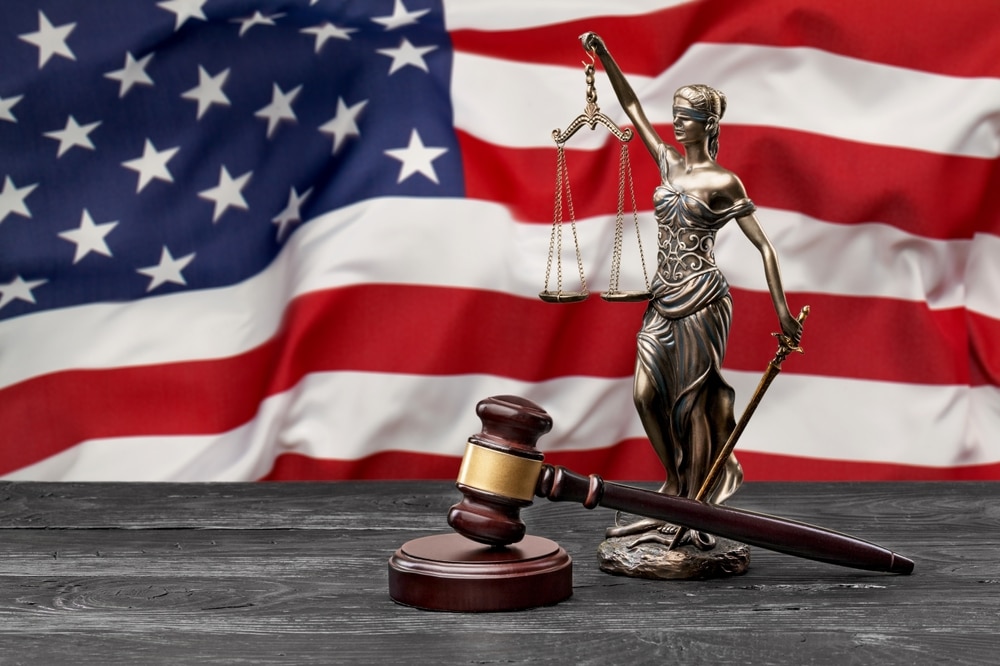 UsFlagWithAStatueOfJusticeJudgeWoodenHammer - Tokenhell Solana and Ethereum NFT Scammers Charged in $22M Rug Pull Scheme