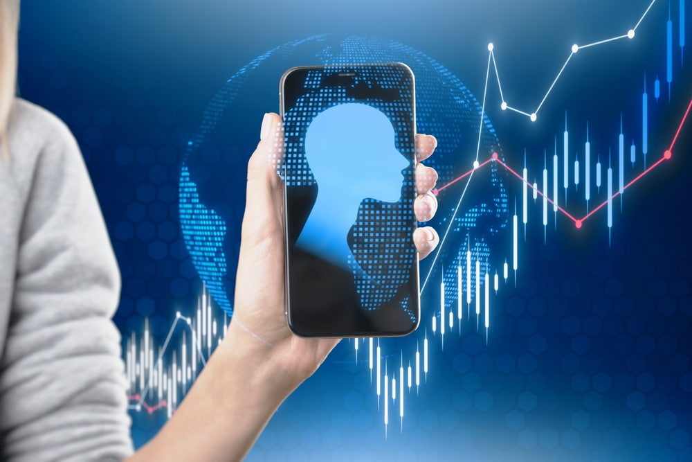 CloseUpOfFemaleHandHoldingCellphoneWithAbstractGlowing - Tokenhell Immediate Profit Now Review – Does this AI Trading Bot Give you a Chance to Shine?